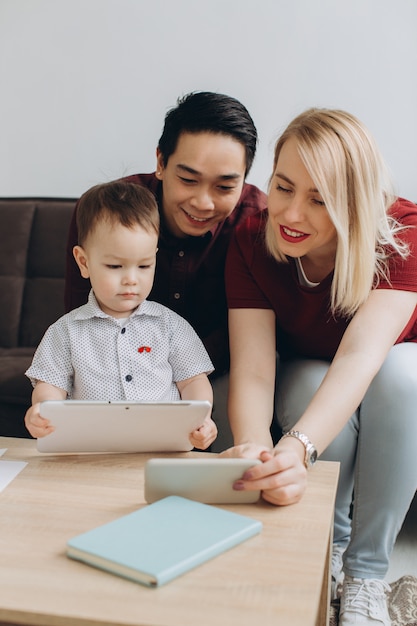 happy-multicultural-family-asian-man-caucasian-woman-with-their-son-watching-video-tablet-phone_1429-5553